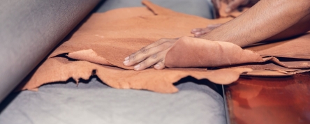 Hands feed raw leather through a press. Photo credit: Bangladesh Labour Foundation.