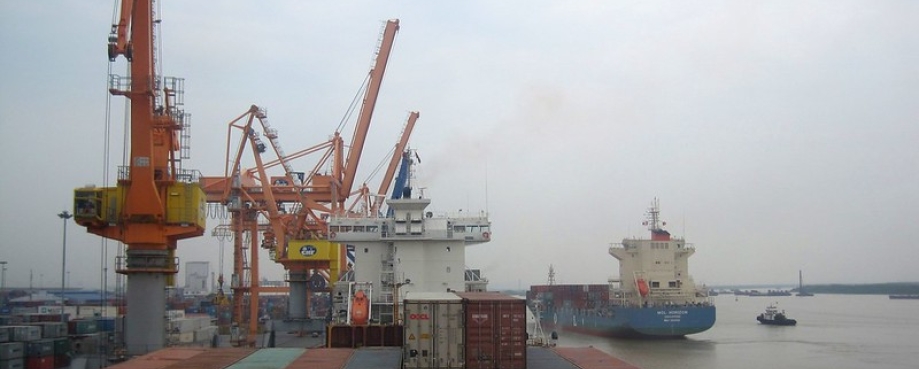 Shipping containers being loaded onto a cargo ship at port. Photo credit: ILO/ Hoa Tran.