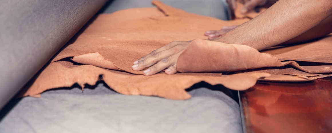 Hands feed raw leather through a press. Photo credit: Bangladesh Labour Foundation.